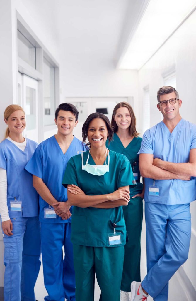 Portrait Of Smiling Multi-Cultural Medical Team Standing In Hospital Corridor